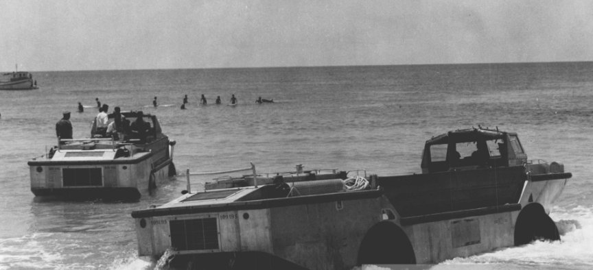 LARC5 amphibious vehicle in surf with surfers